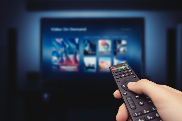 Bild mit einer Fernbedienung vor einem Fernseher zu TV Zusatzprodukten